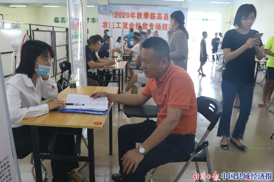 临高县人力资源服务中心主任林鸿刚向招聘工作人员了解企业用工需求（陈建峰 摄）