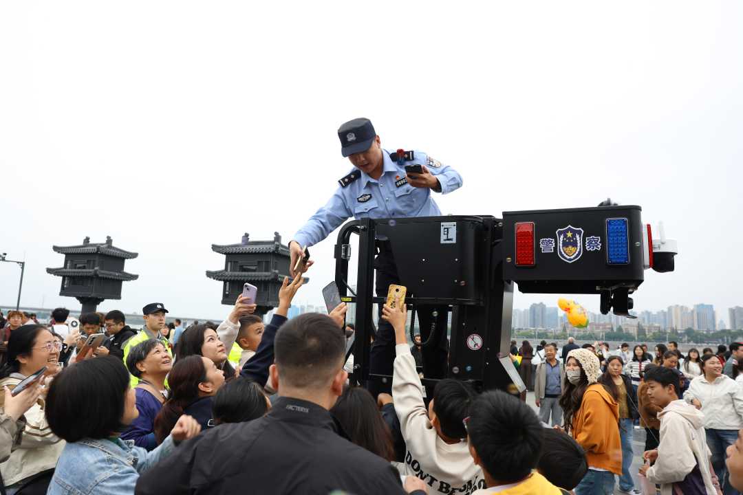 国庆期间，襄阳临汉门广场游人如织，执勤民警在维护现场秩序的同时化身“临时摄影师”，利用瞭望台的较高视野主动帮助游客打卡拍照。