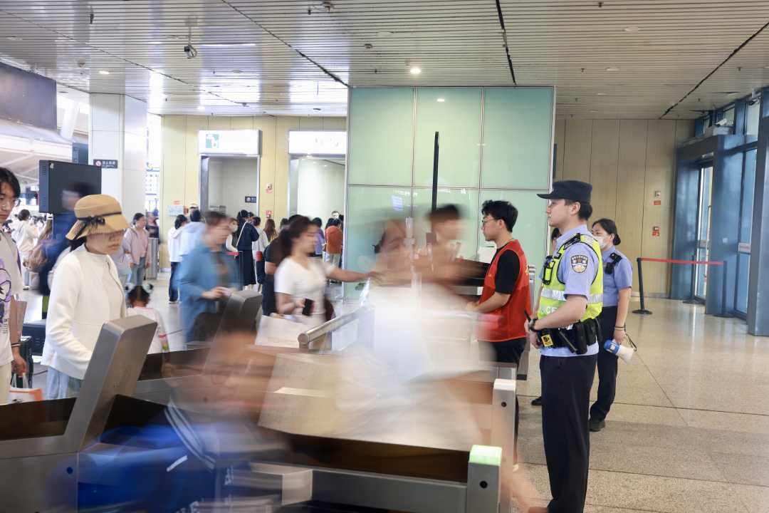 武汉铁路公安处武汉站派出所民警在检票闸机立岗，维护旅客出行秩序。